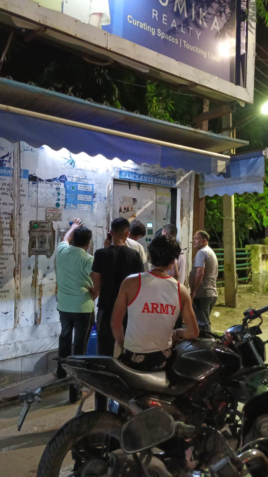 Maintenance engineers checking a kiosk's smart interface on a tablet at an urban transit hub at night